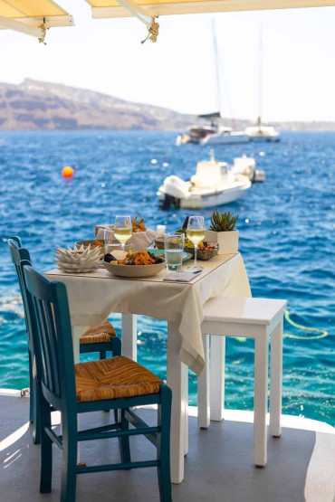 Romantic Sunset Restaurants in Santorini - How to Reserve the Best Romantic Sunset Restaurants in Santorini, Greece Table at the Sea at the Sunset Ammoudi restaurant in Santorini, Greece.