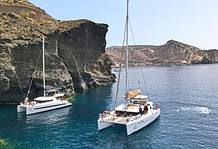 What to Expect and How to Book a Santorini Cruise Catamaran sailing past the Indian rock in Santorini Greece