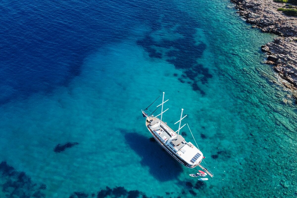 kekova blue cruise - Kekova Blue Cruise Guide: Cabin Charter vs Private Gulet Explained A gulet anchored in one of Bodrum’s quiet coves, surrounded by clear turquoise waters during a Blue Cruise route.