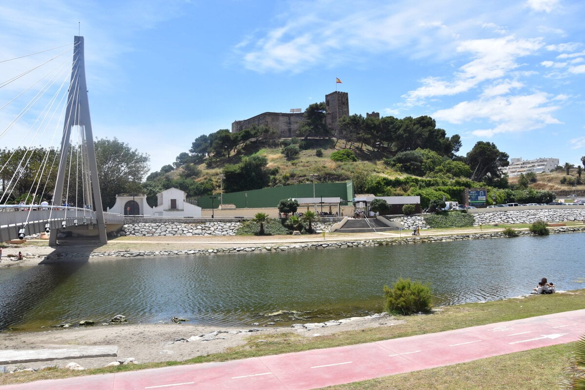 The medieval Sohail Castle on the hill overlooking the river footbridge and beach during late afternoon in Fuengirola