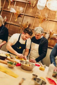 chef help a guest making pasta 